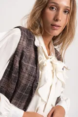 Chaleco sastrero de diseño italiano, con estampado a cuadros en tonos marrones y grises. Presenta escote en V, cierre frontal con botones y un corte entallado.