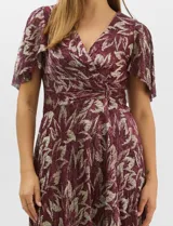 Vestido largo de fiesta con diseño cruzado, escote en V y drapeado lateral en la cintura. Presenta mangas cortas acampanadas y falda amplia con caída fluida. Confeccionado en tejido liviano con acabado plisado y estampado floral metalizado.