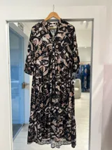 Vestido midi negro con estampado floral en tonos beige y marrones, escote en V con botones frontales y mangas tres cuartos con volados.