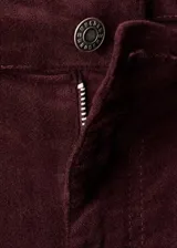 Pantalón jeans flare de terciopelo color bordó, de tiro alto y diseño largo, con cinco bolsillos, trabillas para cinturón y cierre frontal con botón y cremallera.