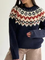 Sweater de cuello redondo con diseño de jacquard estilo nórdico en la parte superior, combinando tonos azul marino, blanco y rojo. Presenta mangas largas y puños acanalados.