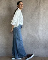 Pantalón de jean azul de tiro medio, con corte wide leg y ruedo deshilachado.