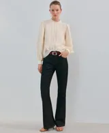 Blusa de color crema con cuello redondo, mangas largas abullonadas y detalles de bordado y puntilla vertical en el frente.