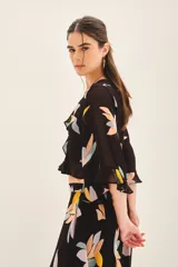 Camisa corta tipo crop top de viscosa georgette con estampado floral. Presenta mangas amplias con volados y detalle de volado en la cintura. Incluye forrería a tono.