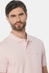 Remera polo de piqué color rosa claro, con cuello y puños en rib, cierre frontal con botones y bordado contrastante en el pecho.