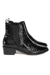 Bota tipo Chelsea de caña baja, confeccionada en cuero vacuno con acabado de charol y textura de reptil. Presenta elásticos laterales negros, puntera redondeada y taco cuadrado bajo.