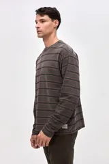 Remera de manga larga con diseño de rayas horizontales en tonos azules. Confeccionada en algodón lavado con textura suave y corte clásico.