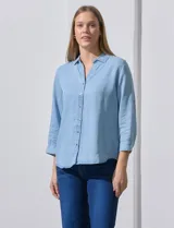 Camisa gris de tencel con cuello con solapa, escote en V y abertura central con botones. Largo de manga regulable con presilla y botón. Ruedo en espalda con tajo.