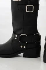 Bota de cuero negra de caña media con hebillas metálicas y taco bajo.