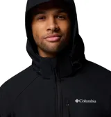 Chaqueta softshell negra con capucha desmontable, cierre frontal completo y bolsillos con cremallera. Presenta logo de la marca bordado en el pecho y puños ajustables.