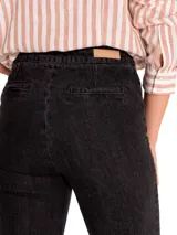 Jeans de denim gris oscuro, estilo bootcut de tiro alto, con costuras frontales verticales que estilizan la pierna y cierre de doble botonadura metálica en la parte delantera.