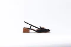 Zapato de cuero negro con talón descubierto y pulsera con hebilla. Tiene un aplique dorado en la capellada y taco de madera.