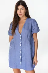 Vestido corto de lino color azul, con escote en V, cierre frontal con botones y mangas cortas abullonadas. Cuenta con cintura entallada con tablas.