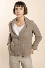 Chaqueta marrón de lana con cuello, solapa y bolsillos ojal. Forro solo en las mangas y terminaciones envivadas. Esquinas redondeadas y mangas con corte en puño que permiten transformarla en manga 3/4. Más larga en la espalda que en la delantera. Abrochadura con dos botones.