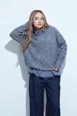 Sweater de tejido suave color marrón con diseño de líneas bordadas en color rojo. Presenta cuello redondo, manga larga y calce relajado.