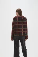 Sweater de tejido jacquard con diseño a cuadros en tonos bordó, negro y beige. Presenta un corte holgado, cuello solapa amplio y cierre frontal parcial con cremallera.