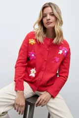 Cardigan de punto color rojo con cierre frontal de botones y bordados de flores en diversos colores. Presenta cuello redondo y mangas largas con puños acanalados.