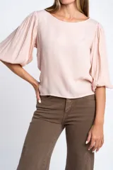 Blusa color rosa pálido, de manga larga abullonada con puño elástico y escote redondo.