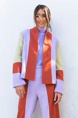 Chaqueta de corte recto con diseño multicolor en bloques de color naranja, lila y amarillo. Presenta cuello mao, mangas largas con puños vueltos y bolsillos laterales.