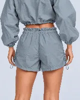 Short gris con cintura tipo clochard con regulador, ajustes con cordón en los laterales y bolsillos. Confeccionado en tejido ultra suave de poliéster y poliamida con protección UV 50+.