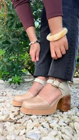 Sandalia de cuero modelo Berlin, con plataforma y taco ancho de madera, punta cuadrada y tira ajustable al tobillo con hebilla metálica.