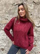 Sweater de punto grueso color borgoña con cuello alto y diseño de trenzas en el frente.