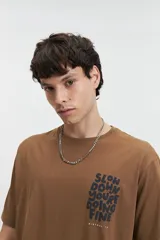 Remera celeste de manga corta con cuello redondo y estampado frontal con la frase "Slow Down You're Doing Fine" en letras blancas con efecto 3D.