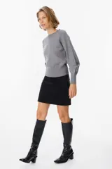 Sweater de silueta holgada en color crudo, con cuello redondo, mangas largas y puños anchos acanalados.