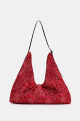 Bolso shopper rojo con estampado tipo bandana y textura plisada. Cuenta con una fina asa de hombro ajustable negra y cierre principal con clip imantado.