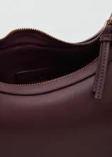 Bolso de hombro tipo hobo en color bordó, con diseño de media luna, cierre de cremallera superior y asa ajustable con hebillas metálicas.