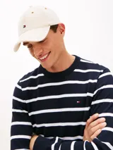 Gorra de béisbol Tommy Hilfiger confeccionada en denim rígido de color beige, con diseño de seis paneles, costuras a contraste, ojales de ventilación y visera curvada con costuras texturizadas. Cuenta con un pequeño logo bordado en el frente y hebilla metálica de ajuste en la parte trasera.