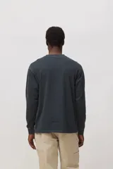 Remera de manga larga color gris oscuro con efecto lavado, cuello redondo y detalle de parche pequeño con logo en forma de X en el pecho.