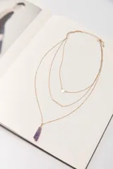 Collar dorado de múltiples capas con cadena de eslabones y cuentas, cadena con dije de triángulo, cadena con dije de barra horizontal y cadena con dije de amatista.