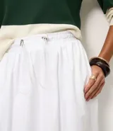 Falda midi de algodón color blanco, con cintura elástica y ajuste mediante cordón con punteras metálicas. Diseño fluido y versátil.
