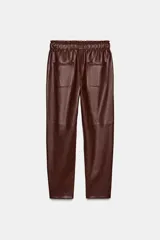 Pantalón de tiro alto confeccionado en material efecto piel, con cintura elástica ajustable mediante cordones, bolsillos delanteros y bolsillos de plastrón en la parte trasera.