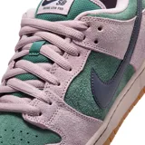 Championes Nike SB Dunk Low Pro confeccionados en gamuza, con base en color verde y superposiciones en tono lila. Cuenta con el característico swoosh en color azul oscuro, entresuela rosada y suela de goma marrón.