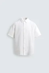 Camisa blanca de lino con corte relajado (relaxed fit), cuello solapa y manga corta. Cierre frontal con botones.