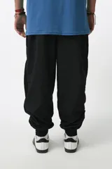 Pantalón de jogging negro de nylon con forro interno de red, corte recto, bolsillos laterales con cierre, cierres en los tobillos y cintura elástica con cordón ajustable.