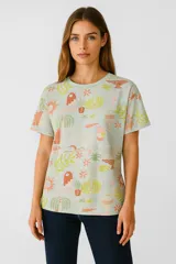 Remera celeste con estampado de flores, palmeras y objetos decorativos en tonos pastel.