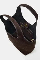 Bolso formato mini shopper confeccionado en piel de ante color topo. Cuenta con doble asa de mano, asa bandolera extraíble, cierre mediante botón imantado y bolsillo interior con cremallera.