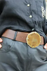 Cinto de cuero azul con hebilla circular de piedra ágata con borde dorado.