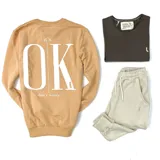 Buzo color naranja con estampa frontal de la frase "It's OK, don't worry" en color blanco.