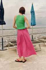 Falda midi con silueta evasé y estampado de cuadros en tonos fucsia y blanco. Presenta cintura elástica con lazo ajustable y detalle de borlas colgantes.