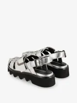 Sandalias plateadas con tiras entretejidas, hebilla lateral y suela track negra.