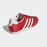 Championes Adidas modelo Taekwondo Lace, de estilo retro inspirado en artes marciales. Presentan un diseño en color rojo con las icónicas tres tiras laterales en blanco, puntera con acolchado 3D y costuras en contraste. Cuentan con suela de caucho de perfil bajo.