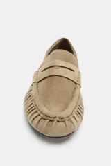 Mocasín plano de mujer en gamuza color beige, estilo driving moc, con detalle de fruncidos y costuras decorativas en la puntera y tira de antifaz.