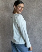 Remera blanca de manga larga con cuello en V y costuras decorativas en contraste. Incluye un lazo ajustable en el cuello con herraje metálico circular.