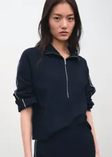 Jersey Cosmus de punto azul marino con cuello alto y cierre frontal de cremallera corta, manga larga y detalles de ribetes claros en las costuras.