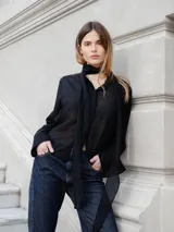 Camisa de corte recto y tejido semitransparente, con cuello mao y cierre frontal oculto por tapeta. Presenta mangas largas con puños anchos y un diseño minimalista.