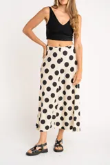 Falda midi color crudo con estampado de lunares negros, corte evasé y cintura alta.